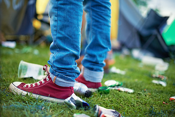 Image showing Feet, event and a person with litter on grass and plastic bottles, cans at an outdoor festival. People at a party, concert with garbage on a field and shoes with pollution for recycling trash