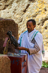 Image showing Man counts collected funds from the faithful outside St. George Church, Lalibela Ethiopia