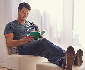 Image showing Man, relax or reading with book on chair in living room for story, literature or novel at home. Handsome male person or young adult for information, knowledge or learning in leisure or break at house