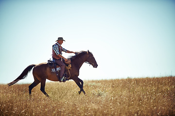 Image showing Cowboy, adventure and man riding horse with saddle on field in countryside for equestrian or training. Nature, summer or rodeo and mature horseback rider on animal running outdoor in rural Texas