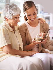 Image showing Family, necklace and elderly mother with woman for present, gift and surprise in living room. Home, pearls and happy daughter with mom giving heirloom on sofa for celebration, birthday and bonding