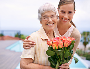 Image showing Senior woman, daughter and portrait with flowers, hug and care for love, bonding and reunion at family home. People, elderly mom and mothers day celebration with connection, gift and smile in garden