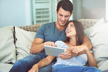 Image showing Happy couple, hug and sofa with tablet for movie, social media or entertainment at home. Man and woman lying in relax with smile on technology for online streaming, series or show in living room