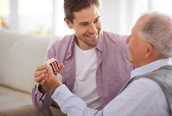 Image showing Senior, man and son or medal on sofa with war badge, pride and honor for military hero in living room of home. Elderly, veteran and retired soldier with medallion for service in army with happiness