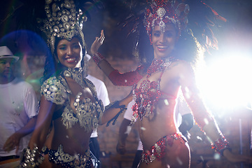 Image showing Portrait, women or dancer with band at carnival in rio de janeiro for brazilian festival with feather costume or smile. People, face or night and dancing, fashion or light for culture or outdoor show