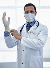 Image showing Portrait, doctor and putting on gloves in mask for protection or safety in hospital. Face, medical professional and man with ppe to prepare for surgery, treatment or prevention of disease for health