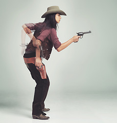 Image showing Western, cowboy and woman with gun in studio for motion, speed and shooting with standing ready. Female person, weapon and serious expression with pistol for character, halloween and costume design