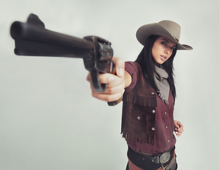 Image showing Cowgirl, portrait and gun pointing or western costume with confidence on white background, weapon or mockup space. Female person, face and revolver in studio or old west Texas, accessories or bandit