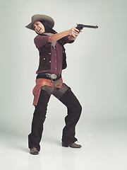 Image showing Western, woman and cowboy with gun in studio for fashion, nervous and scared to shoot on grey background. Female person, vintage and outlaw with pistol for wild west, costume and character with hat