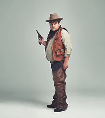 Image showing Portrait, man and cowboy with a gun, serious and proud person on white studio background. Face, model and guy with pistol or firearm with danger or warning with Halloween costume, confidence or Texas