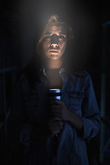 Image showing Portrait, horror and torch for light with woman on black background to hide from fear, panic or terror. Stress, depression and mental health with scared young person in dark for danger or violence