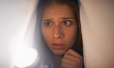 Image showing Flashlight, scared and woman with blanket on bed with anxiety, stress or risk for mystery. Torch, fear and young female person with duvet for protection of horror, terror or danger with panic.