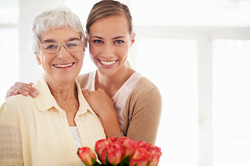Image showing Senior woman, daughter and portrait with bouquet, present or care for love, hug or reunion at family home. People, elderly mom and mothers day celebration for connection, gift or flowers in apartment