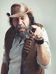 Image showing Old cowboy, point and angry face at studio, costume and pipe for western portrait looking scruffy. Senior guy, upset hat and dirty male for texas, grey background and annoyed for accuse gesture