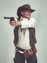 Image showing Cowboy, senior man and shooting gun, weapon or pistol in studio with costume isolated on a white background. Western, sheriff and mature person with revolver, aiming and scared with fear in Texas
