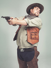 Image showing Cowboy, man and shooting gun in studio, weapon and pistol with western costume isolated on white background. Plus size, criminal or funny person with revolver, guess aim or scared with fear in Texas