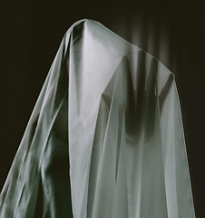 Image showing Horror, dark and scary ghost in sheet on black background with haunting silhouette. Supernatural, spooky and shadow hand of spirit, lost soul or monster in studio with paranormal fear of death