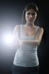 Image showing Woman, fear and scared or flashlight for search in studio, anxiety and stress for risk in mystery. Female person, nervous and lamp in dark against black background, caution and danger on halloween