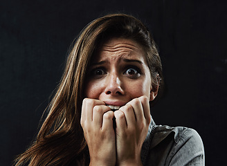 Image showing Portrait, mental health and woman biting nails in studio on black background for reaction to fear or panic. Face, stress and horror with scared young person in dark for drama, nightmare or terror