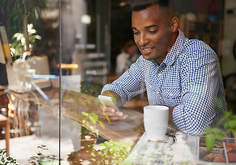 Image showing Coffee, window and man with smartphone at cafe for social media, communication and networking. Person, smile and technology in restaurant for texting, message and scrolling on website online