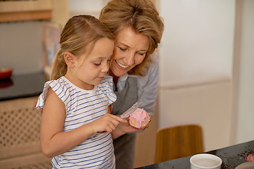 Image showing Woman, child and icing cupcake in kitchen for baking decoration with grandmother, bonding or ingredients. Female person, girl and recipe for sweet dessert at counter or teaching, helping or support