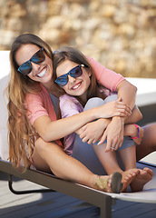 Image showing Portrait, smile and mother on vacation with daughter outdoor in sunglasses for summer, travel or holiday. Family, love and mom hugging girl child on poolside deck chair for bonding, trip or getaway