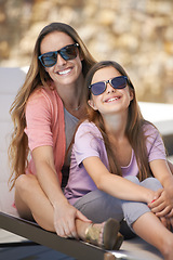 Image showing Portrait, love and mother on vacation with daughter outdoor in sunglasses for summer, travel or holiday. Family, smile and mom hugging girl child on poolside deck chair for bonding, trip or getaway