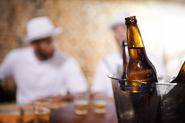 Image showing Beer bottles, alcohol and beverages with men by bar, pub or nightclub for drinking, socializing or partying. Ciders, ice bucket or glasses on counter at tavern, lounge or restaurant for entertainment