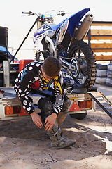 Image showing Motorbike, race and sports with man getting ready for off road adrenaline, competition or training outdoor. Boots, adventure and dirtbike hobby with person in gear on trailer for performance