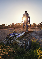 Image showing Bike, off road sports and man with helmet on track at sunset for competition, race or training. Challenge, fitness and motorbike with person in sportswear gear outdoor for action or power from back
