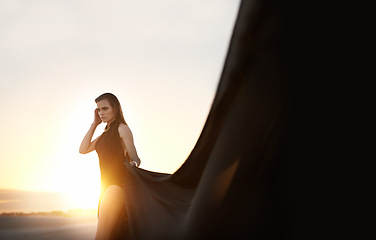 Image showing Sunset, woman and fabric in wind outdoor for summer holiday, vacation or travel. Fashion, person and silk in the air for freedom, adventure and breeze in nature with serious girl thinking on mockup