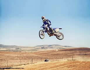 Image showing Person, jump and dirt bike of professional motorcyclist in the air for trick, stunt or race on outdoor track. Expert rider on motorbike or scrambler in dunes or extreme sport with blue sky mockup