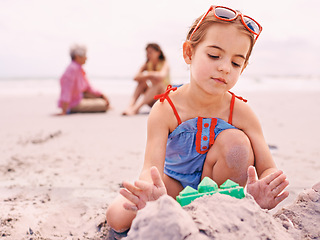 Image showing Child, beach and sandcastle building on holiday for summer travel with family for environment, playing or swimwear. Girl, seashore and outdoor in Australia with parents or recreation, fun or vacation