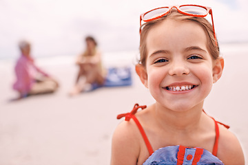 Image showing Portrait, relax and little girl on beach in summer with family for travel, holiday or vacation. Face, smile and sunshine with happy young child on sand by ocean or sea for tropical weekend getaway