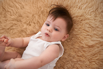 Image showing Top view, carpet and adorable toddler in home, relax and happy on floor of nursery in room for resting. Child, playing and face of infant after nap in house for kid, comfortable and cute baby