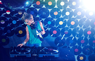 Image showing Woman dj, headphones and vinyl records in night club for party with turntable, lights and lens flare. Gen z female person, retro or mixing decks at event with energy, techno and music in Berlin disco