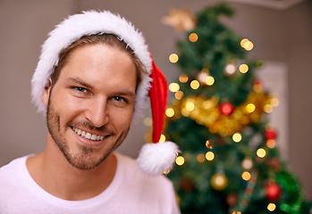 Image showing Man, smile and hat for Christmas, portrait and house with bokeh on tree for festive celebration in holiday for season. Male person, happy and excited with joy on face to relax in home for break