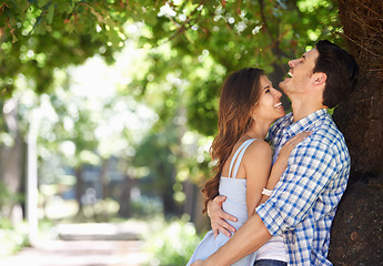 Image showing Young couple, laughing and hug with love under the trees in the park and enjoying sunshine views in the summer sun. Cheerful, affection outdoor and romantic partners bonding with a nature lifestyle