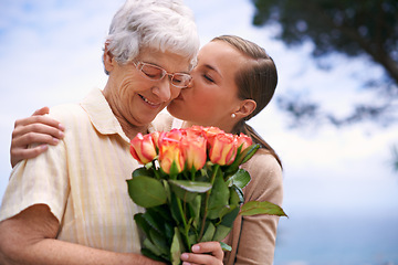 Image showing Senior woman, daughter and kiss with flowers, hug and care for love, bonding and reunion at family home. People, elderly mom and mothers day celebration with connection, gift and bouquet in garden