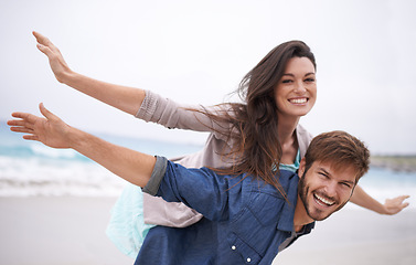 Image showing Airplane, happy and couple with piggyback on beach in summer for love, travel and freedom on vacation in California. Portrait, ocean and face with smile for fun on holiday, trip or adventure together