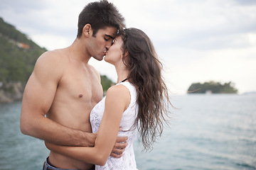 Image showing Summer, holiday and couple kiss by sea in vacation, water and outdoor for date in nature for romance. Partners, woman and man together to travel, journey and adventure in ocean for love with hug