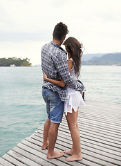Image showing Couple, jetty and embrace by ocean on vacation, love and relax by water on summer holiday. People, hug and bonding for relationship in outdoors, support and back on weekend trip to sea or nature