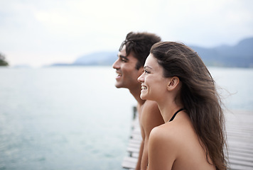 Image showing Couple, jetty and travel to ocean on adventure, love and relax by water on summer holiday. People, swimwear and bonding for relationship in outdoor, support and smile on weekend trip to sea or nature