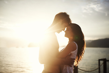 Image showing Sunset, couple and touch face at ocean for holiday, vacation or travel together in summer on lens flare. Happy man, woman and romance at sea for connection, care or love on adventure by water outdoor