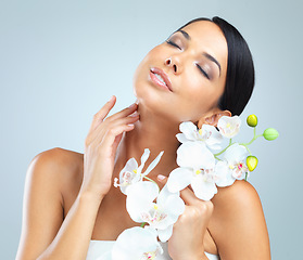 Image showing Flowers, skincare and woman with shine, cosmetics and person on grey studio background. Model, luxury or girl with aesthetic or natural with facial or dermatology with glow or soft skin with wellness