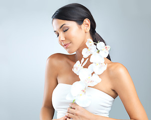 Image showing Flowers, wellness and woman with dermatology, shine and person on a grey studio background. Model, luxury or girl with aesthetic or natural with facial or skincare with glow and beauty with cosmetics