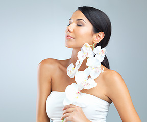 Image showing Flowers, skincare and woman with beauty, glow and person on a grey studio background. Model, luxury or girl with aesthetic or natural with facial or shine with dermatology and smooth skin with health