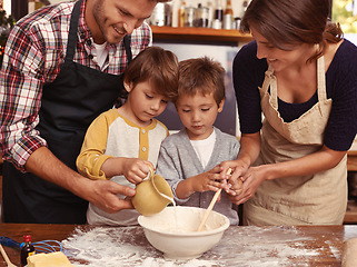 Image showing Family, smile and kids baking in kitchen, learning or happy boys bonding together with parents in home. Father, mother or children cooking with flour, food and brothers pour milk in bowl at table