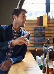 Image showing Businessman, counter and order drink in pub after long day at work, relax and hospitality industry. Male person, buying and beer for enjoyment after job for happy hour, table and hand sign for waiter