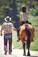 Image showing Back of woman, cowboy or horse riding on countryside farm as equestrian for training, sport or learning. Walking, teaching or people in Texas, outdoor environment or stable for practice on saddle